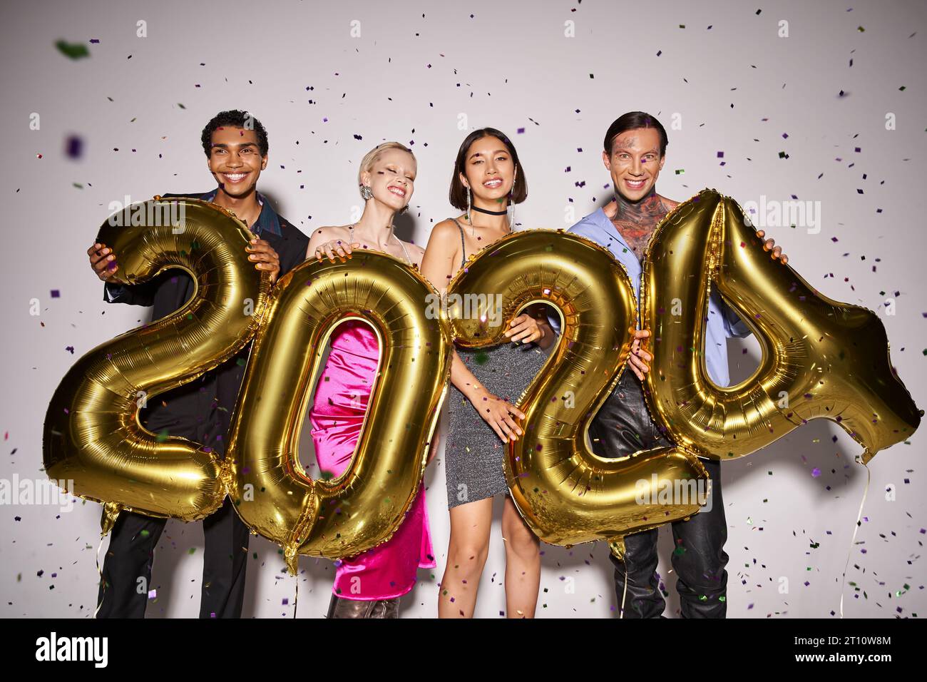 multiethnic friends holding balloons with 2024 numbers near falling confetti, New Year party fun Stock Photo