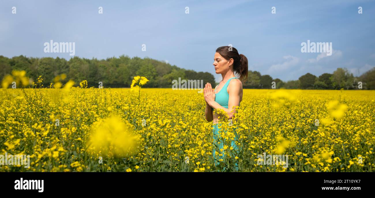 Woman meditating in a yellow rapeseed field Stock Photo