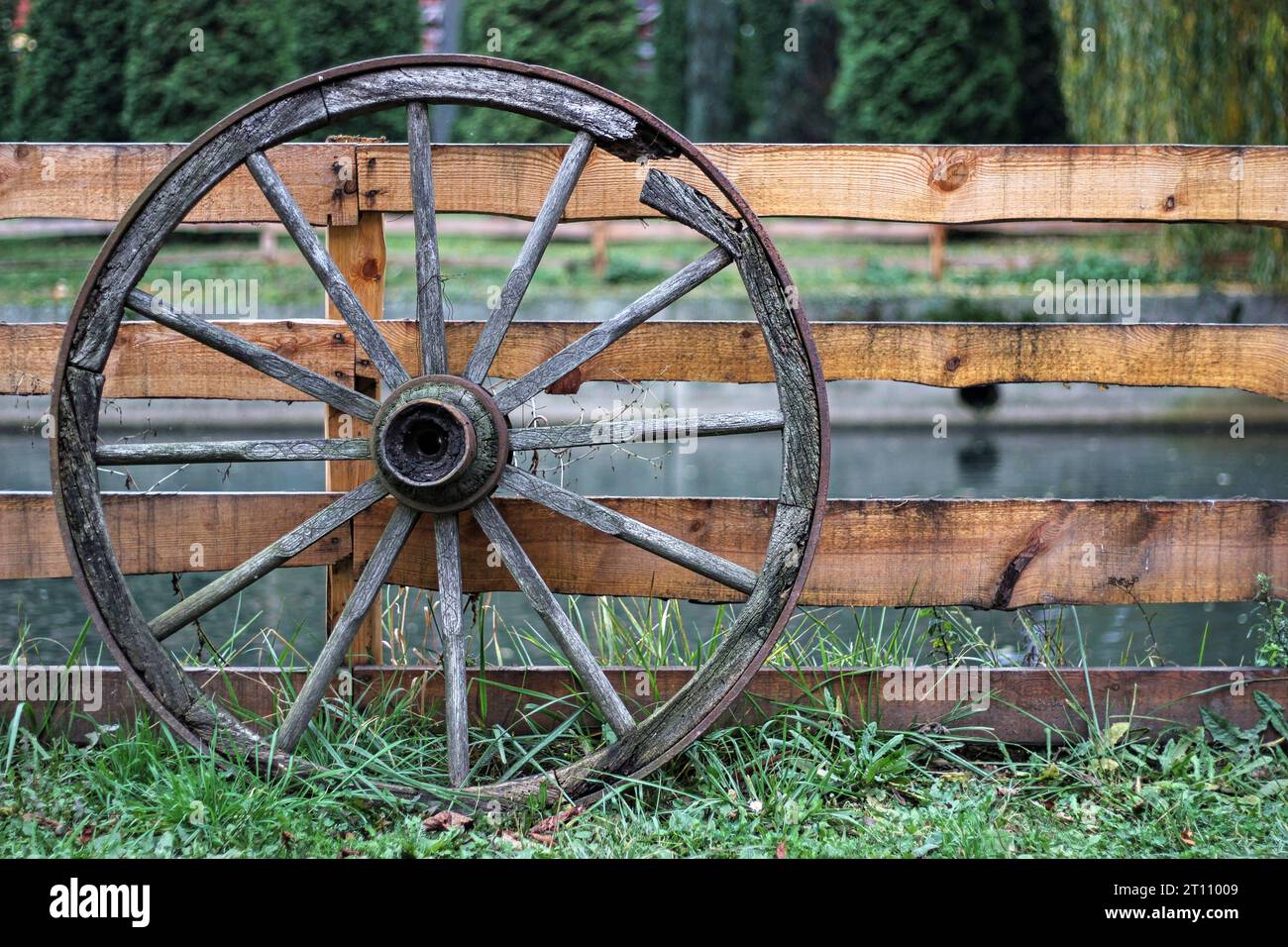 old wooden wheel leaning against a fence Stock Photo - Alamy