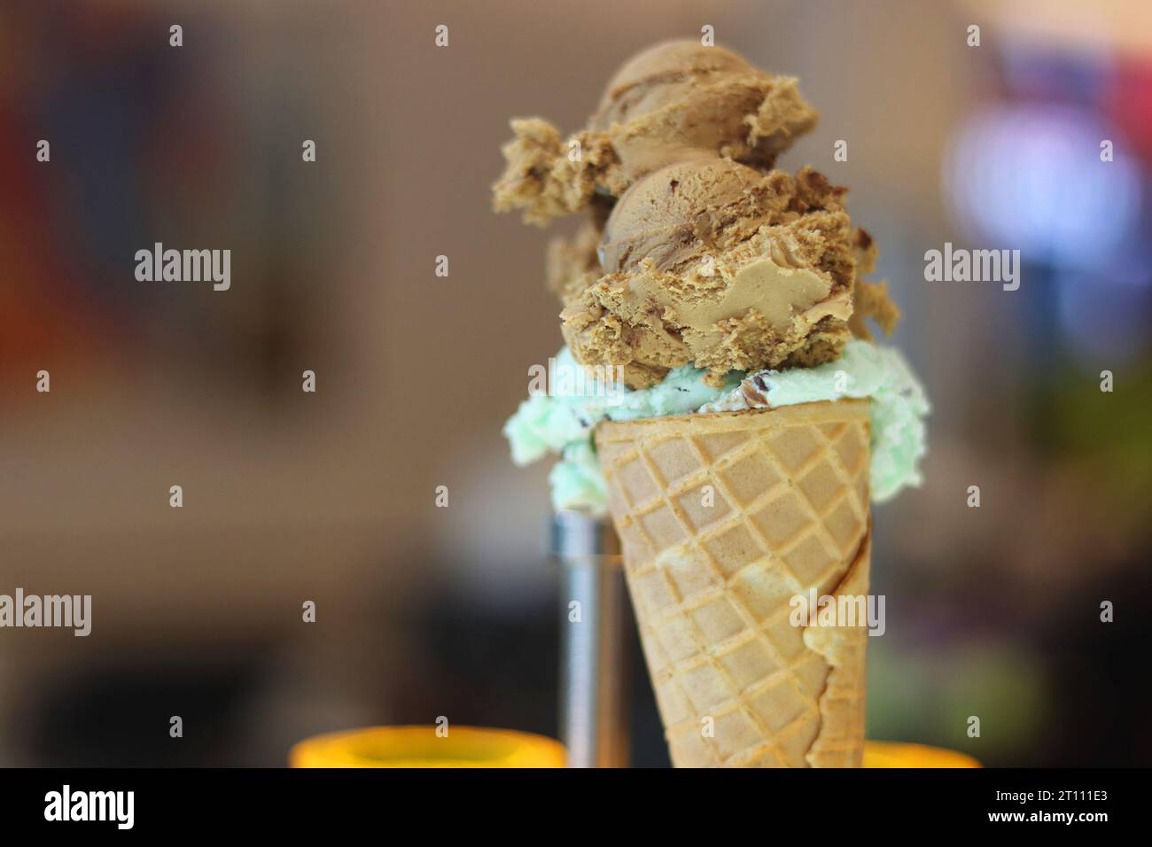 Ice cream waffle cone. Homemade ice-cream in the metal holder. Mint and nougat ice cream. Caramel phistachios ice cream. Copy Space. Selective focus. Stock Photo