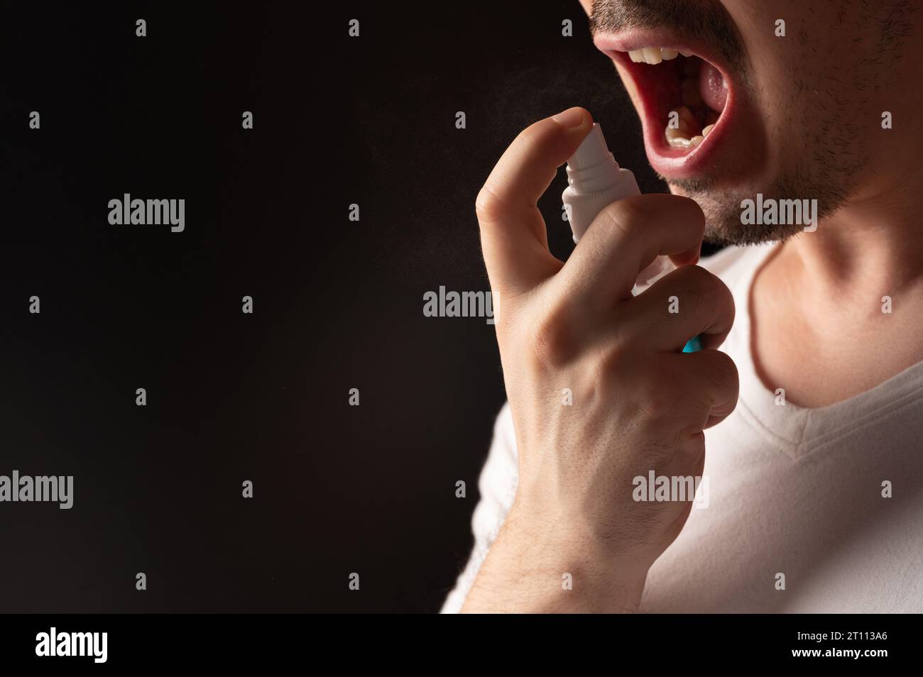 Man spray his throat close up view isolated on black background Stock Photo