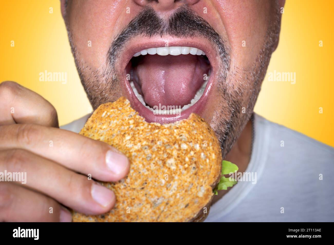Irresistible craving for junk food. Closeup of a hungry man biting