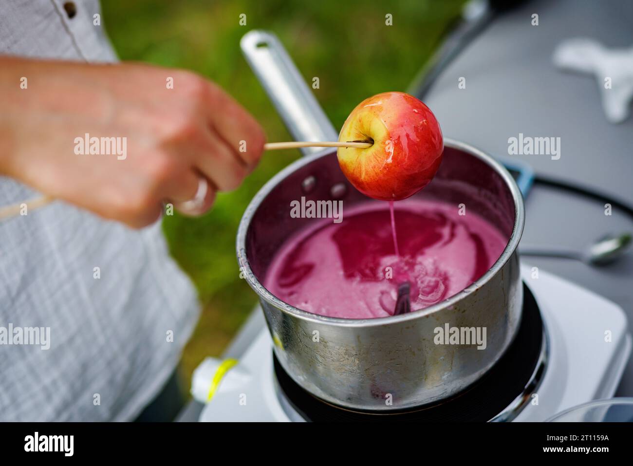 Dipping candy apple into glass bowl with caramel Stock Photo Alamy