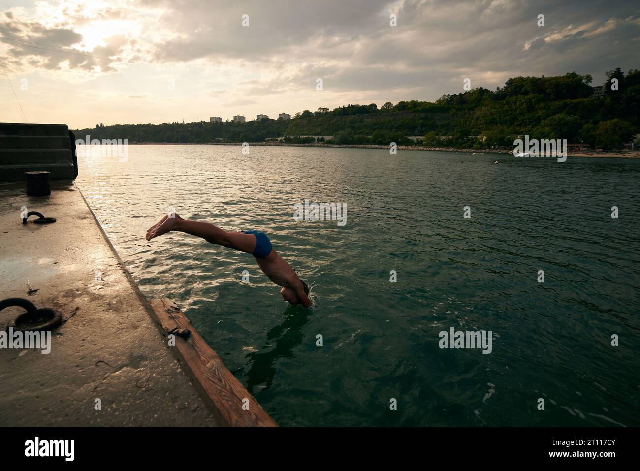 8 years old boy dives into the sea from a pier. Hot summer day Stock ...