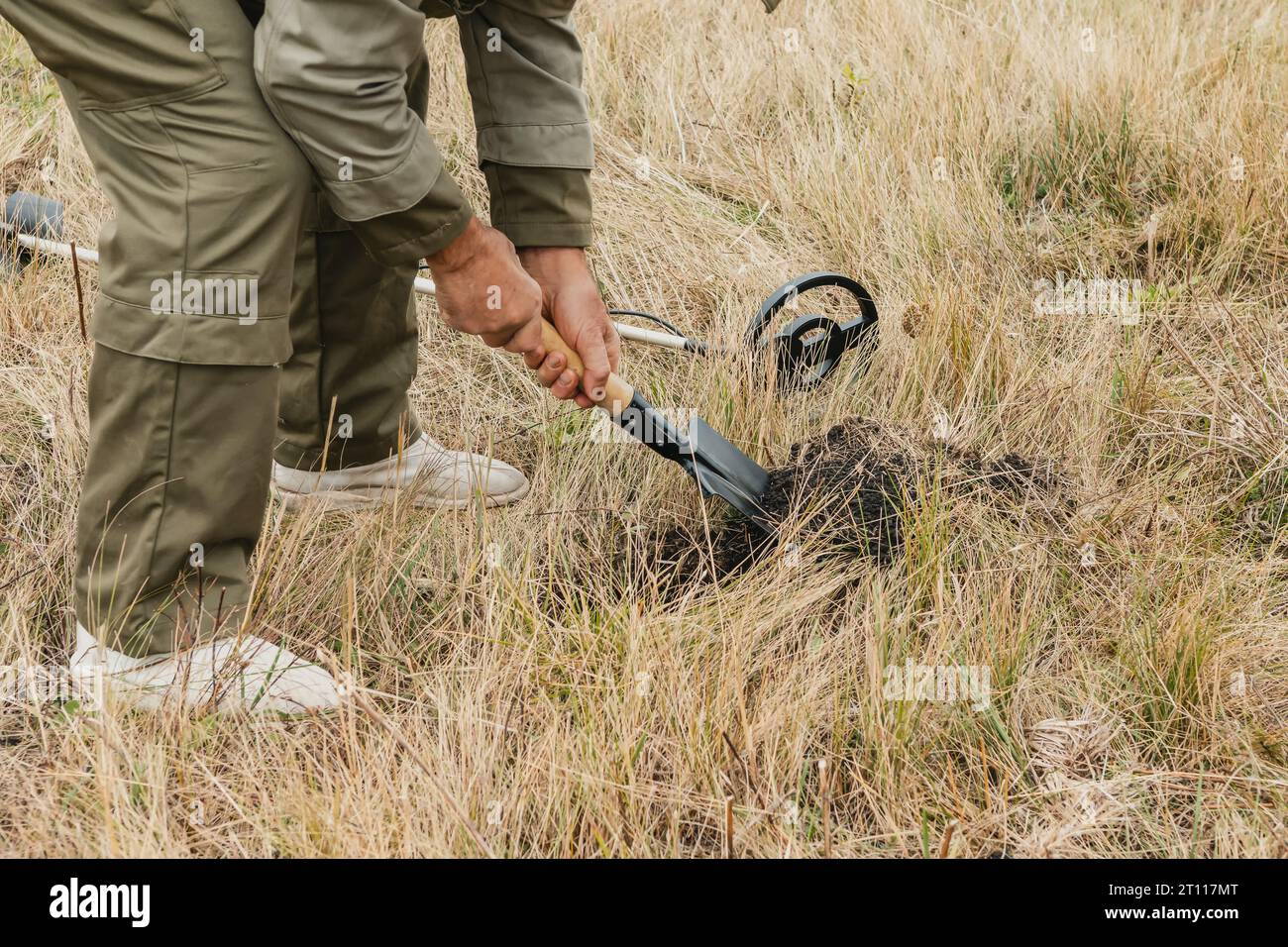 Man with electronic metal detector device working on outdoors. Close-up photography of searching antiques process. Stock Photo