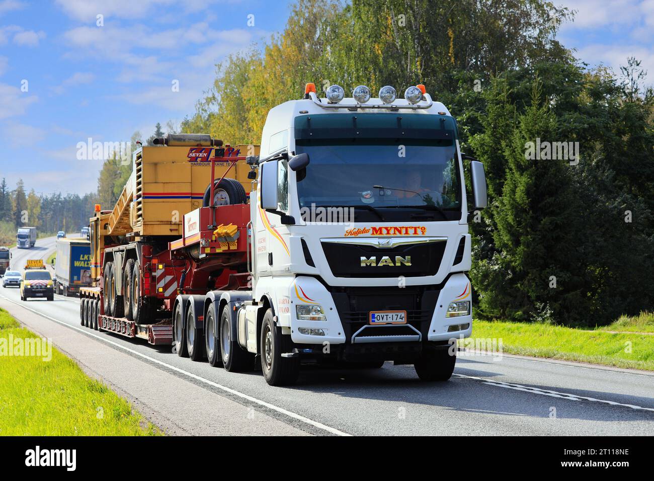 MAN TGX 33.580 truck transports SevenLift harbour crane on low bed trailer as exceptional load, escort car follows. Raasepori, Finland. Sept 22, 2023. Stock Photo