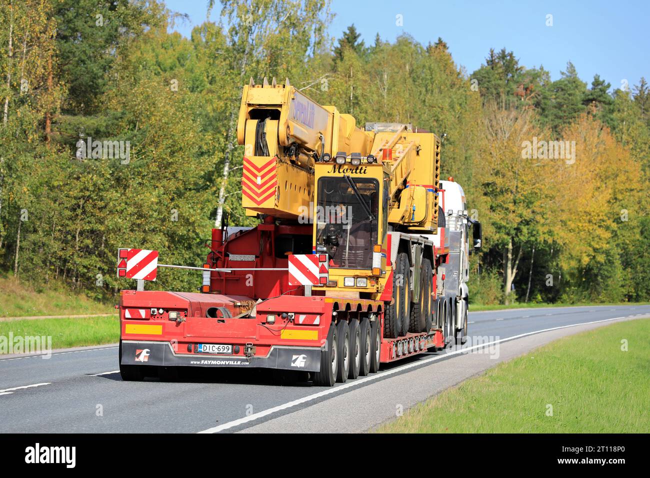 MAN TGX 33.580 truck transports SevenLift harbour crane on low bed trailer as exceptional load on highway 25. Raasepori, Finland. Sept 22, 2023. Stock Photo