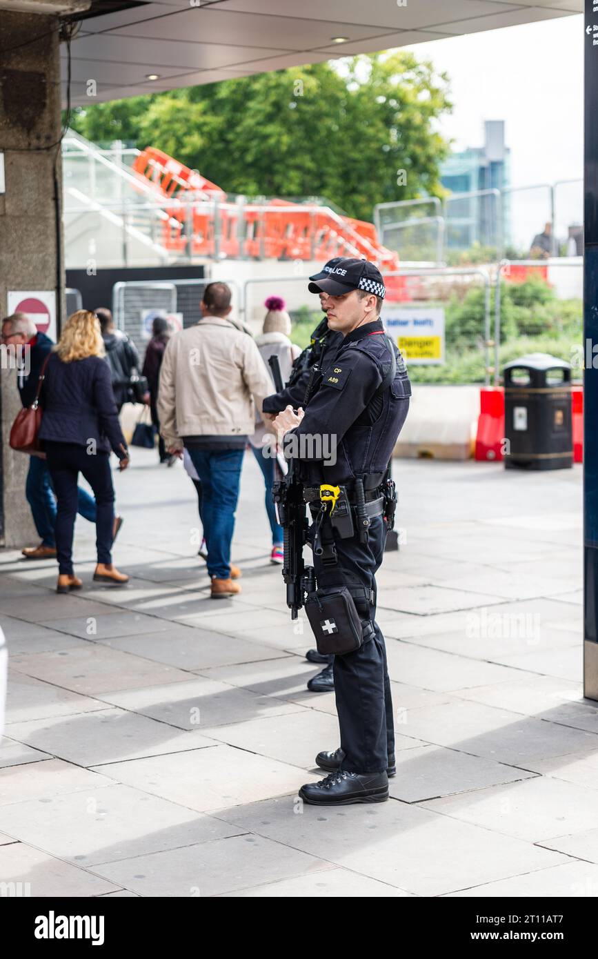 Armed police in London watching over passing public outside Tower Hill railway station, London, UK. Authorised Firearms Officer in tourist area Stock Photo