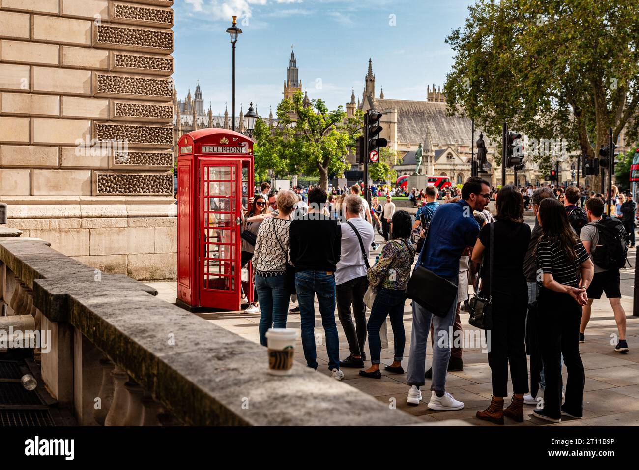 London, England, 07th October 2023: People are waiting in front of a red telephone box at Great George Street for taking pictures. Stock Photo