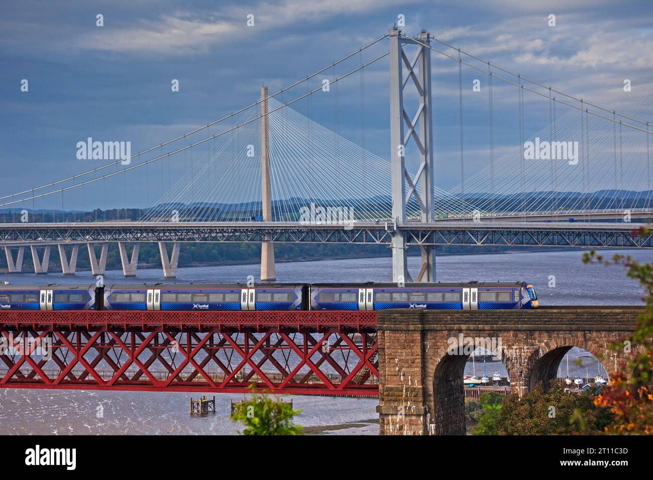 Scotrail diesel train crossing Forth Rail Bridge with Forth Road Bridge and Queensferry Crossing in background, North Queensferry, Fife, Scotland, UK Stock Photo