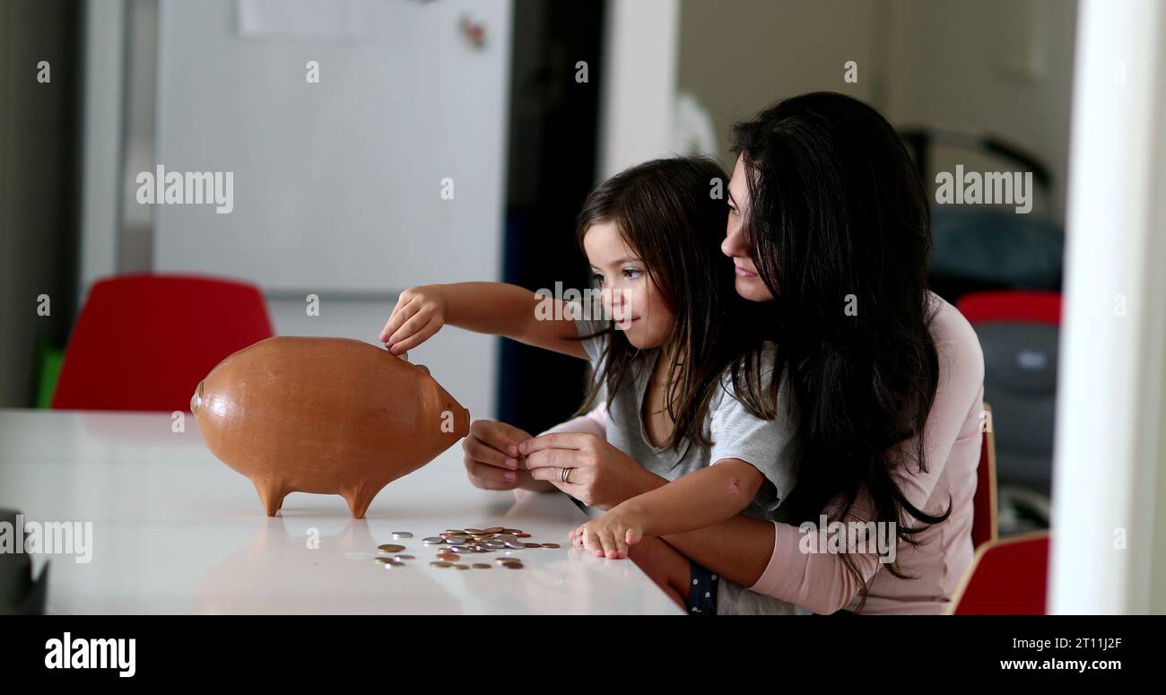 Parent and child saving money by adding coins inside piggy bank Stock ...