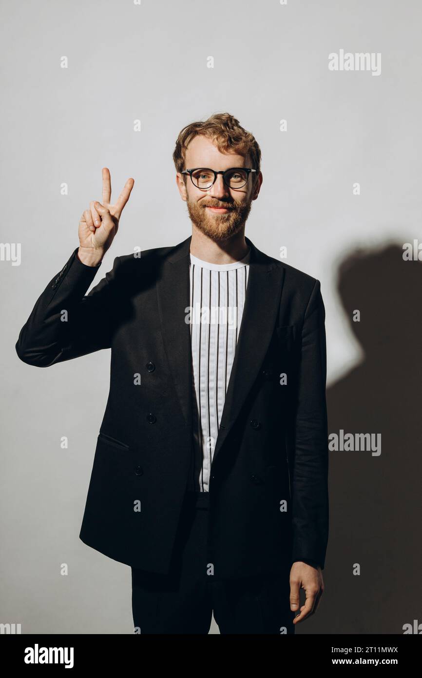 Young man in black jacket with party glasses on color background. Stock Photo