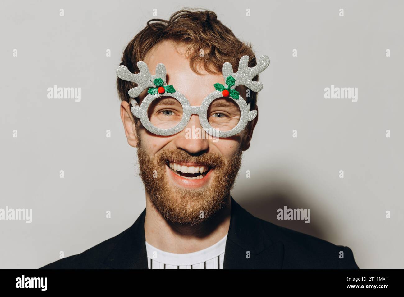 Young man in black jacket with party glasses on color background. Stock Photo