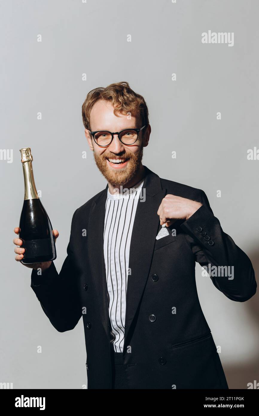 Celebration of the new year. Red-haired young man with a bottle of champagne isolated on a white background. Stock Photo