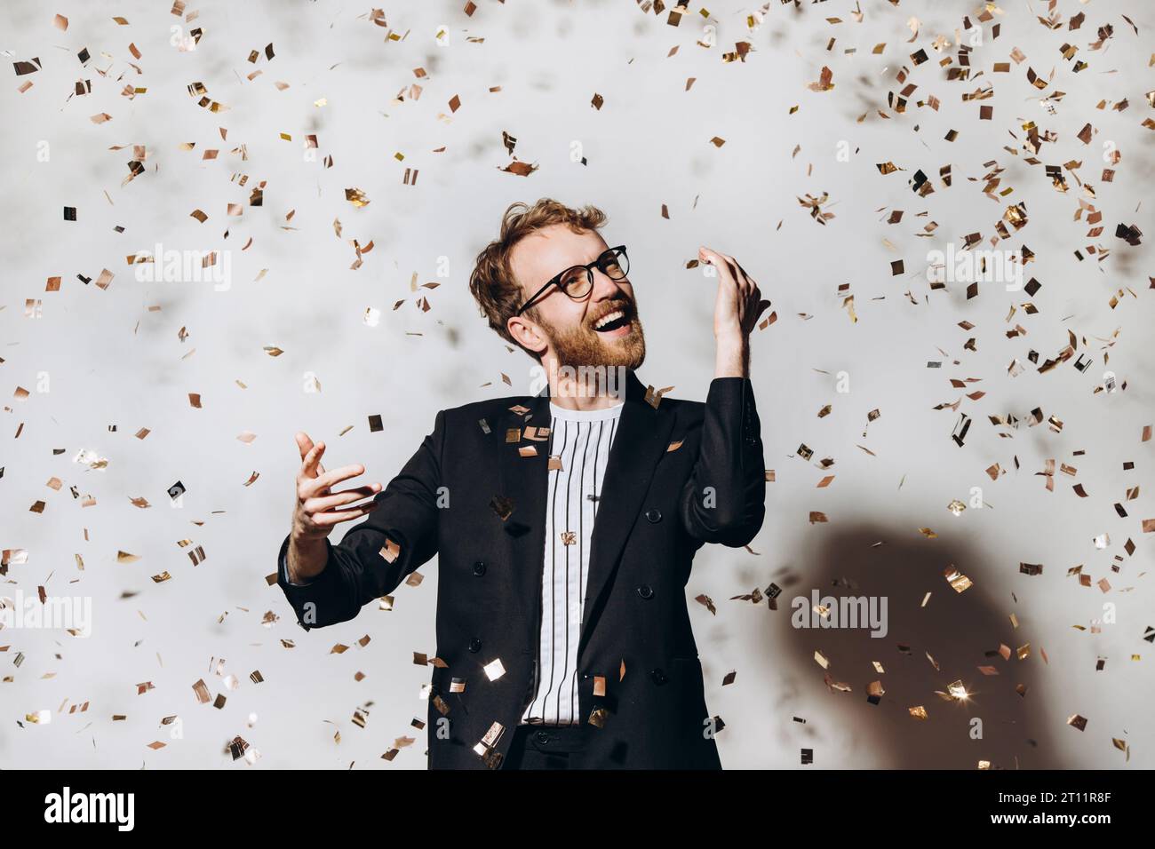 Celebration time. Portrait of a happy guy dancing under glittering confetti. Stock Photo