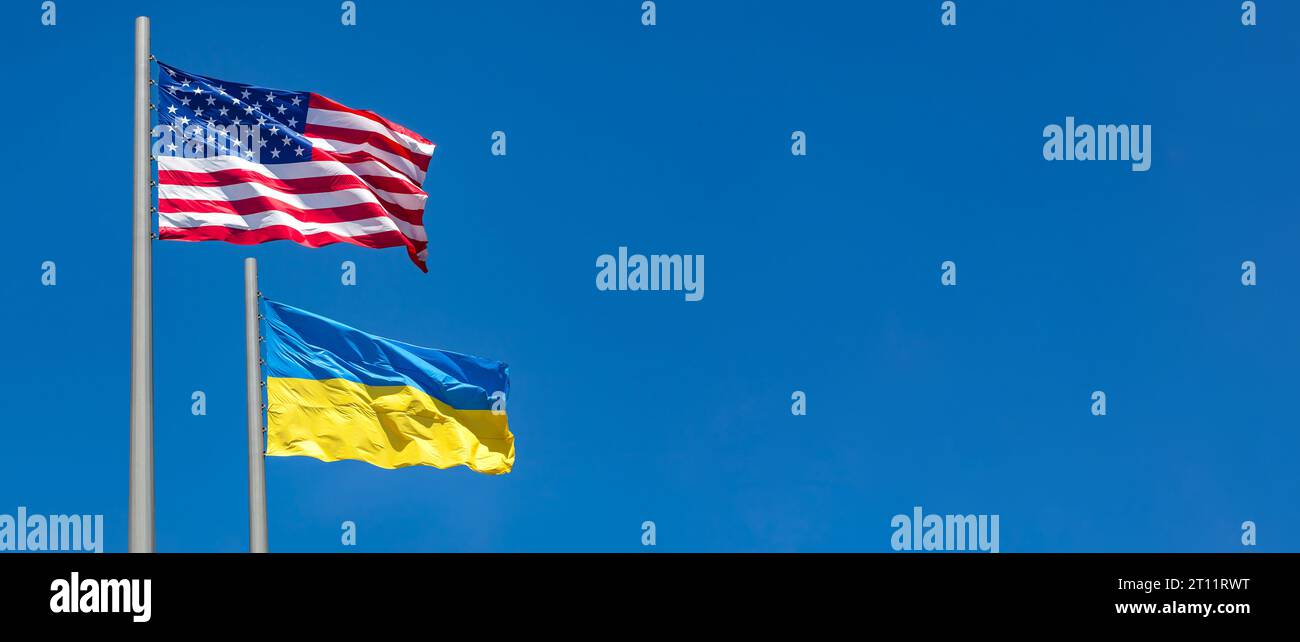 flags of United States and Ukraine waving in the wind against blue sky ...