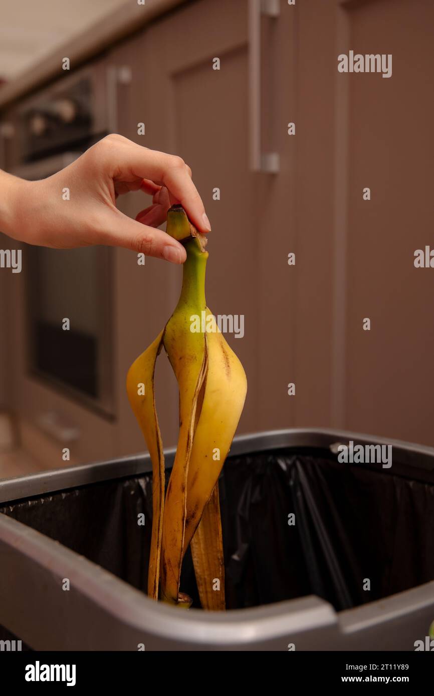 Woman putting banana peel in a trash bin. Kitchen and home Stock Photo