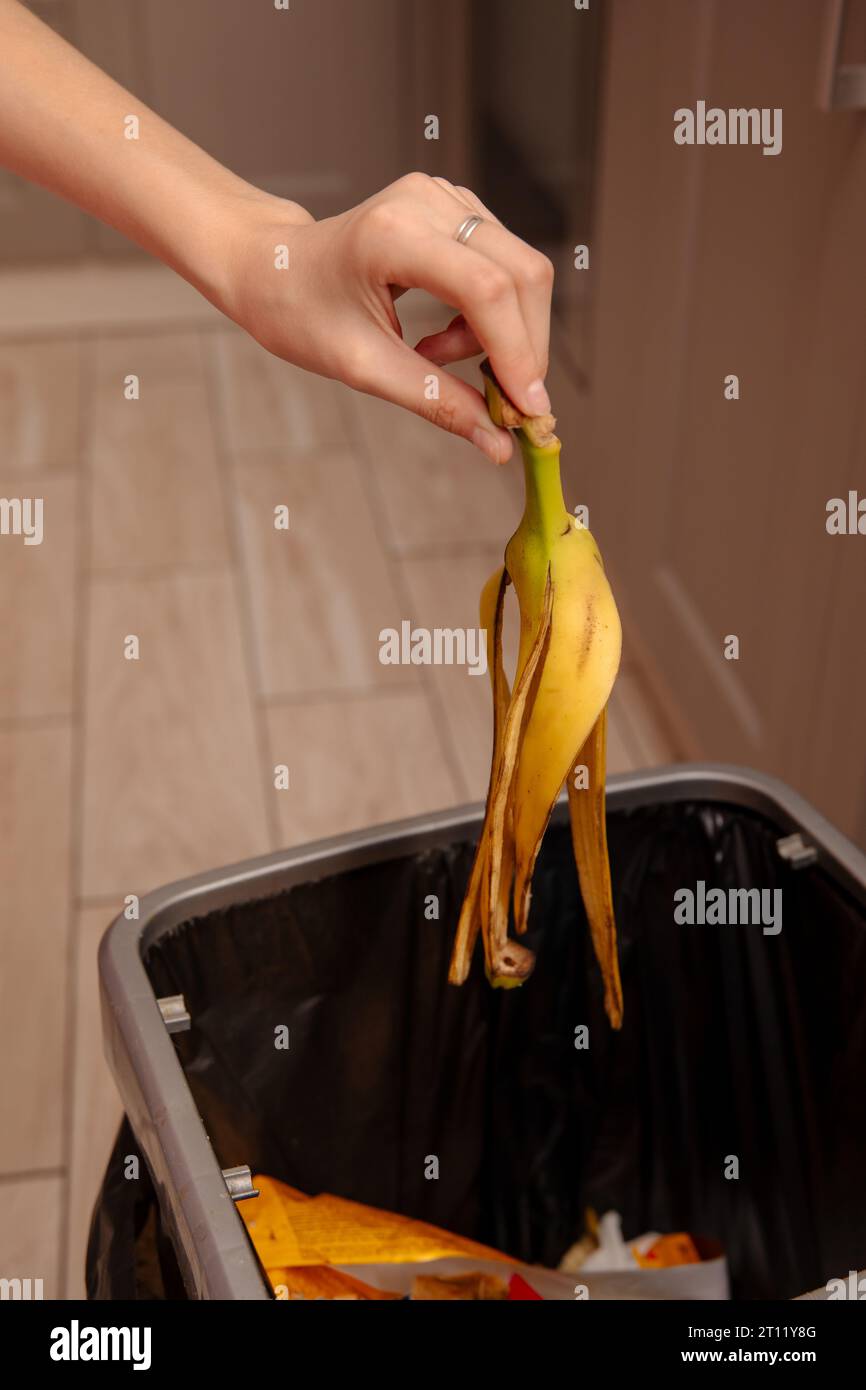 Woman putting banana peel in a trash bin. Kitchen and home Stock Photo