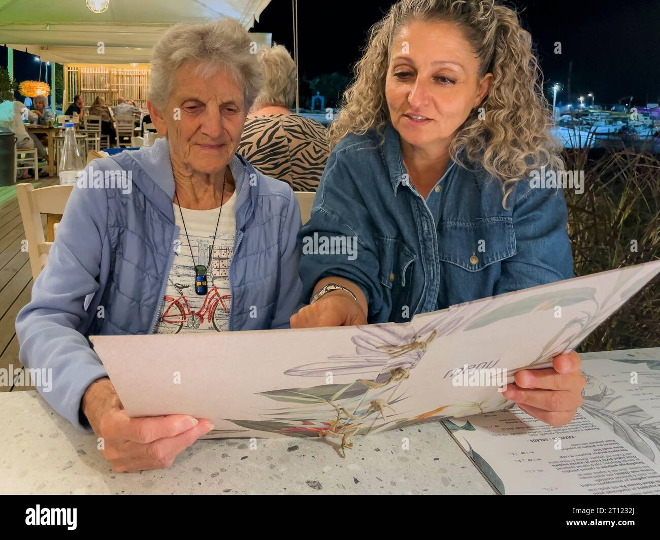 Malia, Crete, Greece, Europe, 01 OCT 2023. Women reading a menu in a Greek restaurant, Malia, Crete. Stock Photo