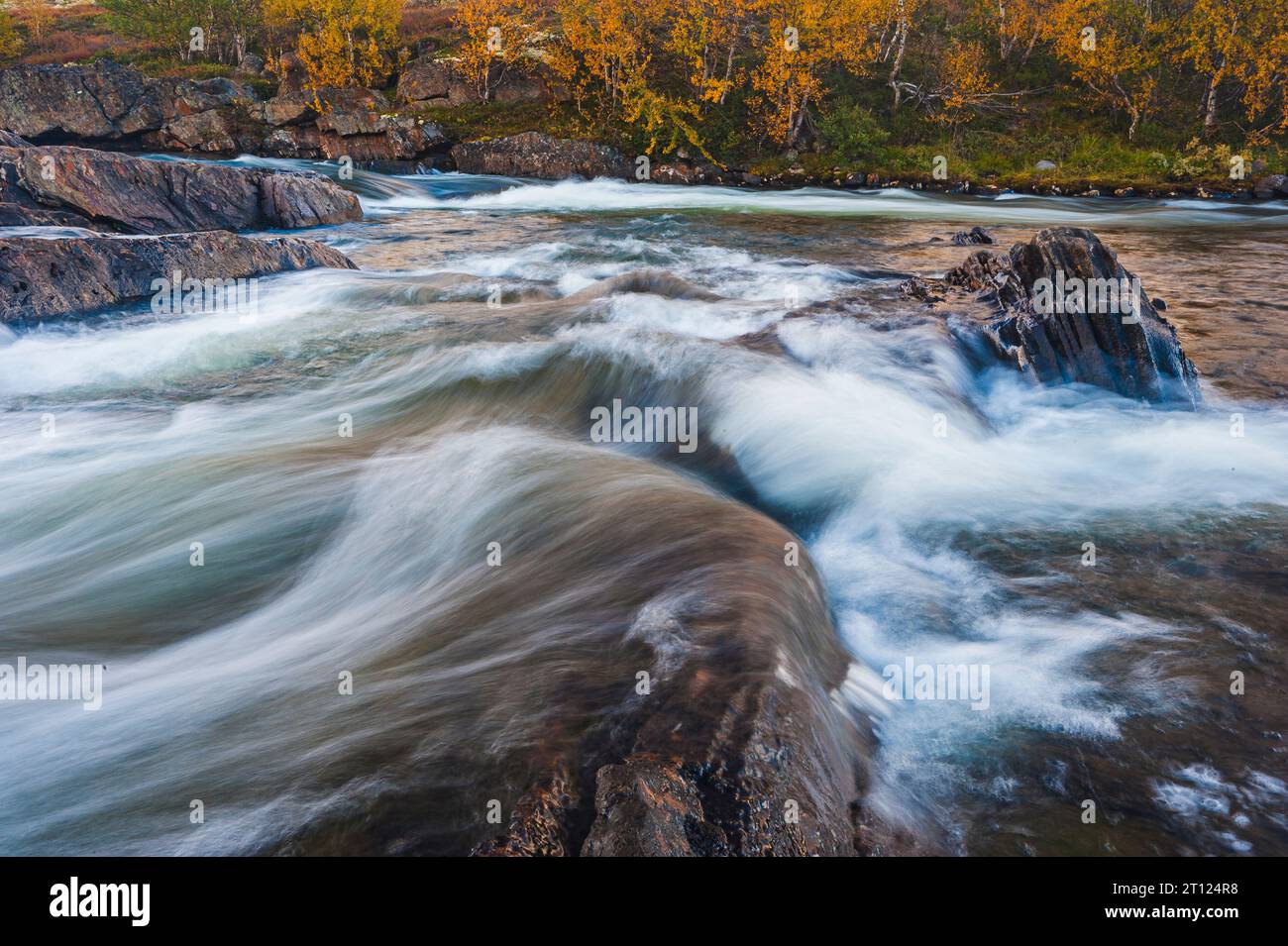 An autumn river with rapid flowing water and scenic landscape. Stock Photo