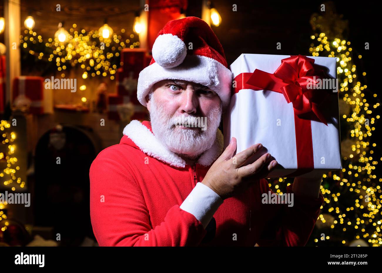 Merry Christmas and Happy New Year. Santa Claus with Christmas gift box. Serious bearded man in Santa Claus costume with present gift box. New Year Stock Photo