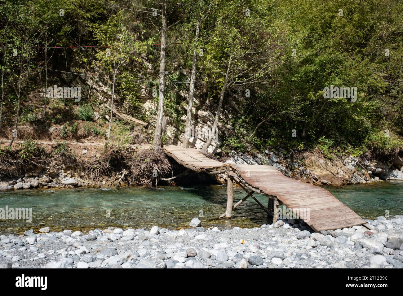 A makeshift wooden bridge over a stream at River Shala resort village on Lake Komani, northern Albania Stock Photo