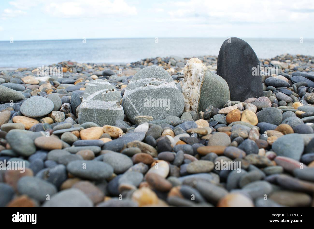 A row of stones on a rocky beach. Various pebbles and stones. Stock Photo