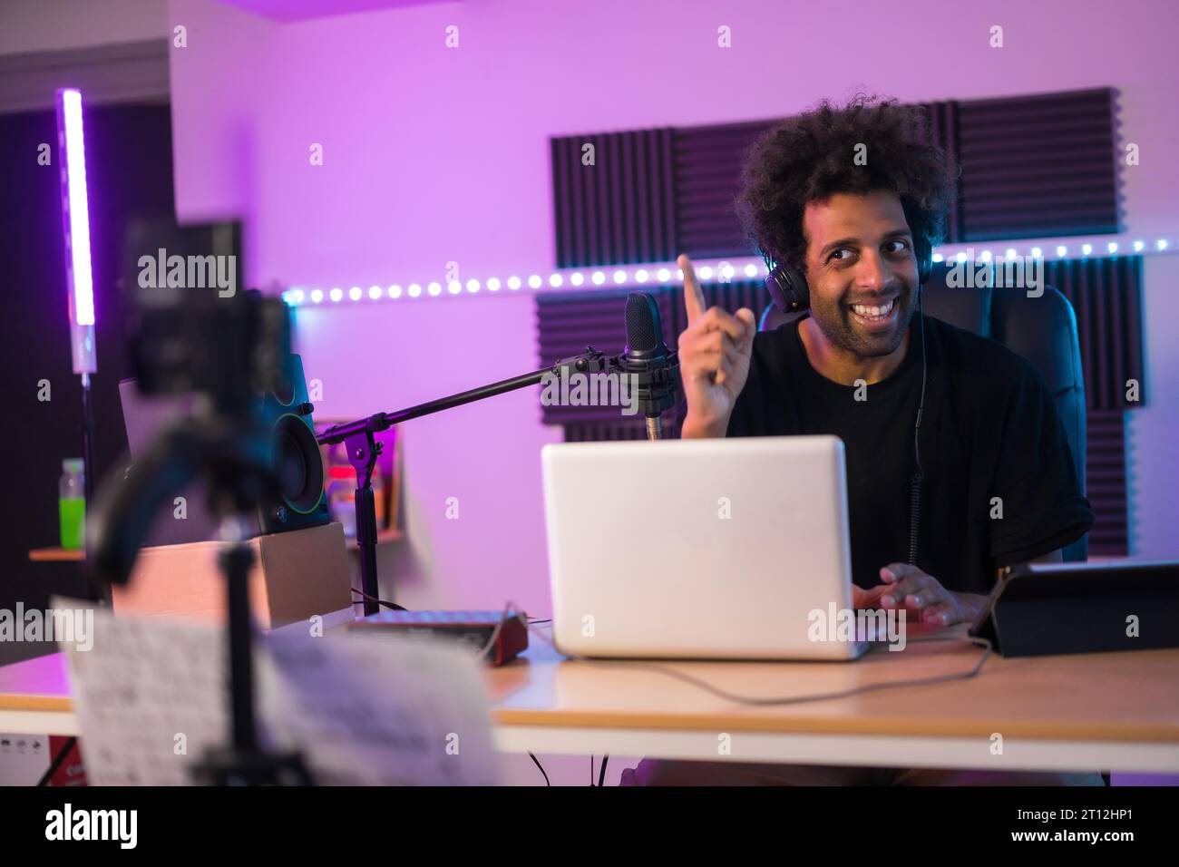 Cheerful and cool streamer recording a video tutorial in a music production studio with neon lights Stock Photo