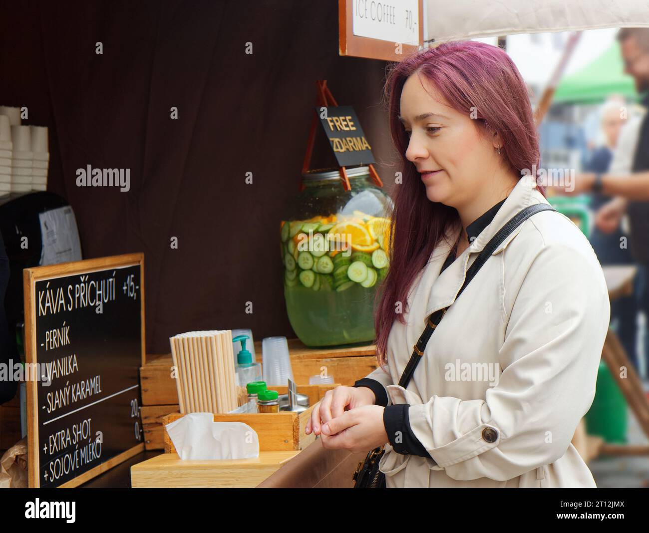 Pretty young woman standing at a coffee stall reading her coffee menu at the Farmers Street Food Market in Prague Stock Photo