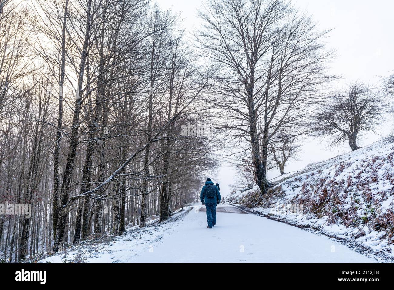 A young man walking on the path to climb Mount Aizkorri in Gipuzkoa. Snowy landscape by winter snows. Basque Country, Spain Stock Photo