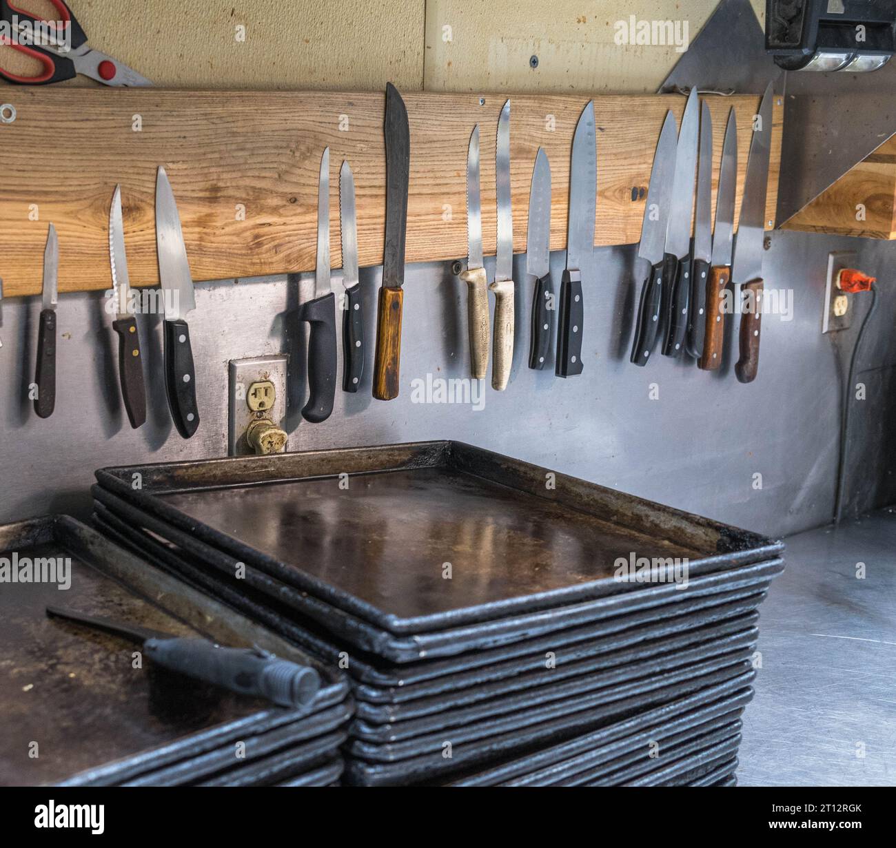 Metal cooking, baking trays and different sized knives in the kitchen