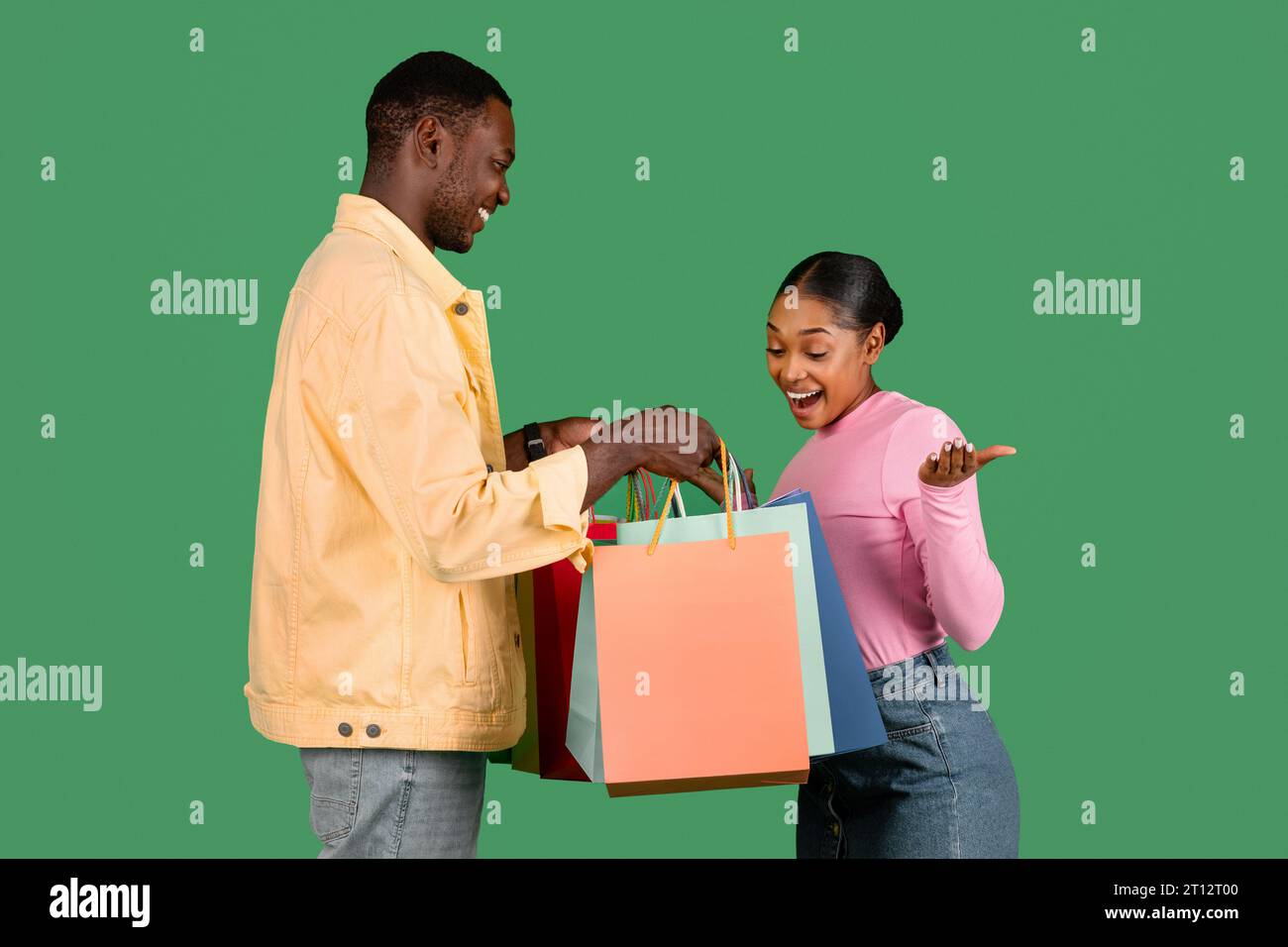 Loving young black guy giving his excited girlfriend shopping bags