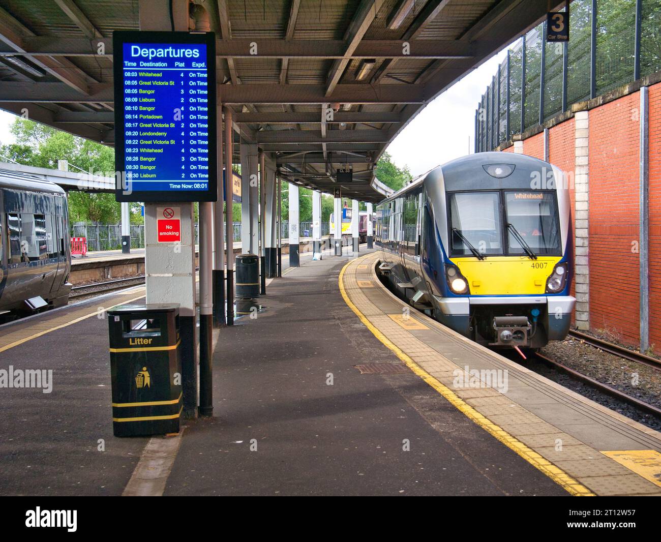 A local commuter train arrives at an empty platform in Lanyon Place Station in Belfast, Northern Ireland, UK. A display shows the time at 0801 Stock Photo