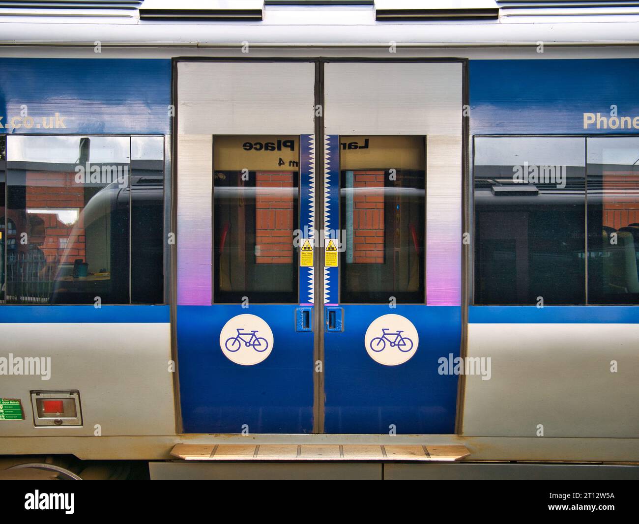 Closed railway carriage doors on a Translink train in Northern Ireland, UK. Two cycle signs indicate that the transportation of cycles  is welcome on Stock Photo