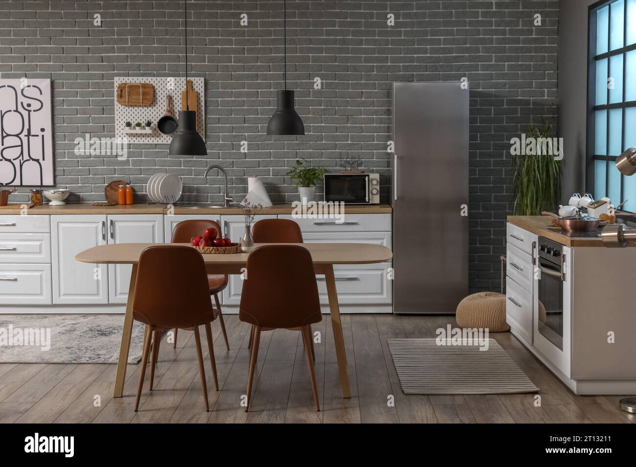 Interior of modern kitchen with white counters, dining table and fridge ...