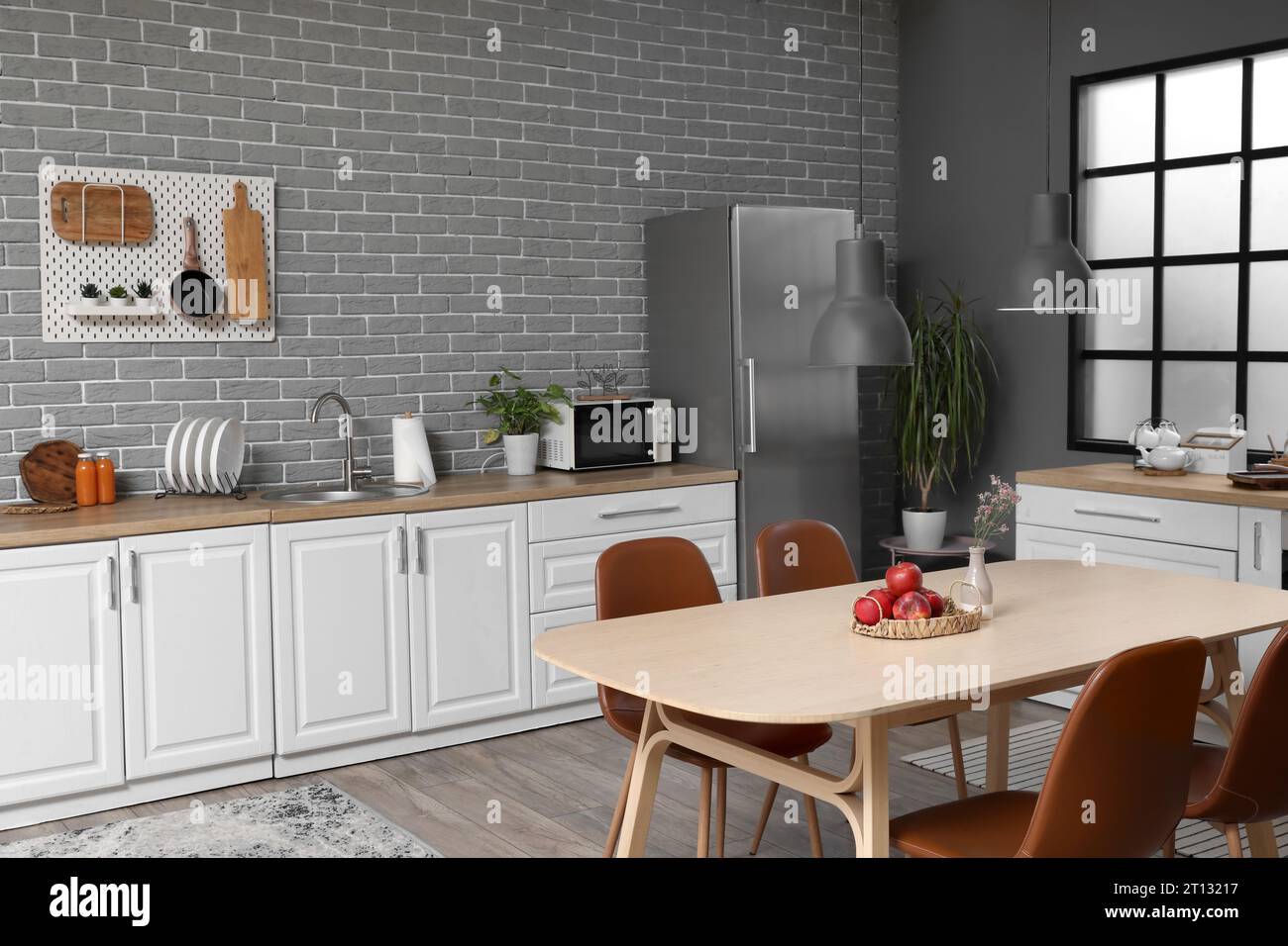 Interior of modern kitchen with white counters, dining table and fridge ...
