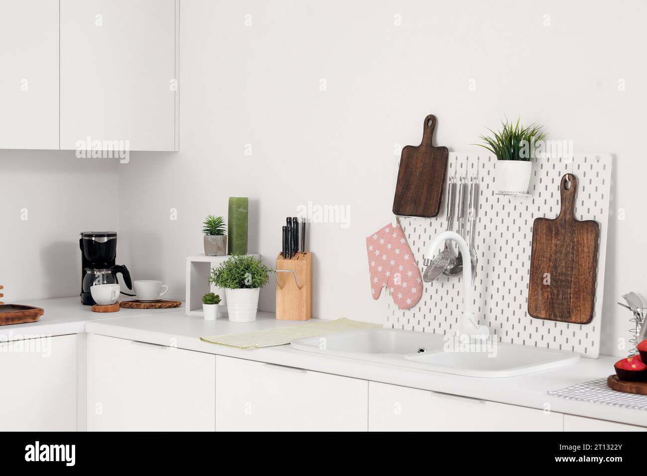 White kitchen counters with cutting boards, pegboard, sink and utensils Stock Photo