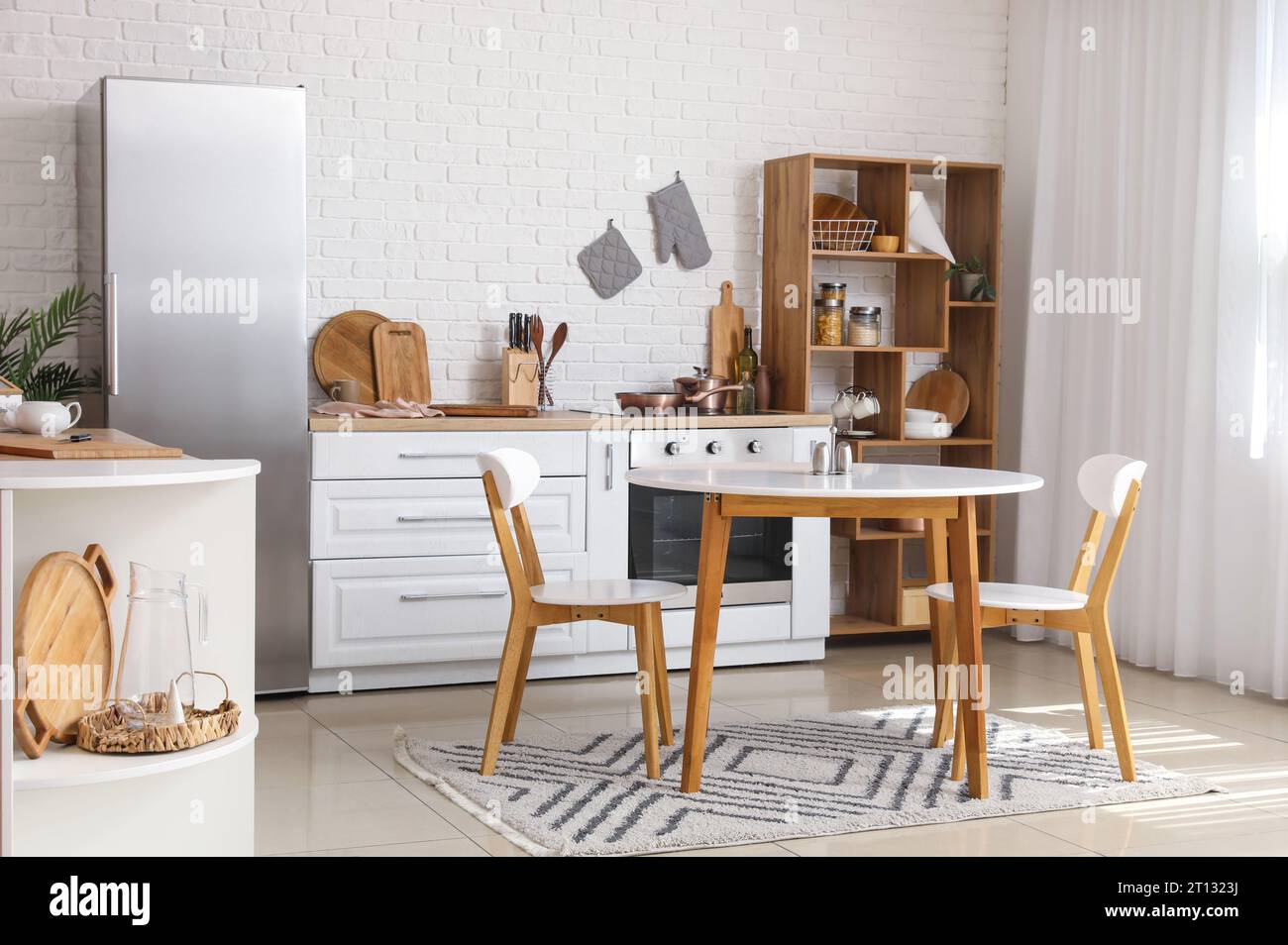Interior of light kitchen with white counters, fridge and dining table ...