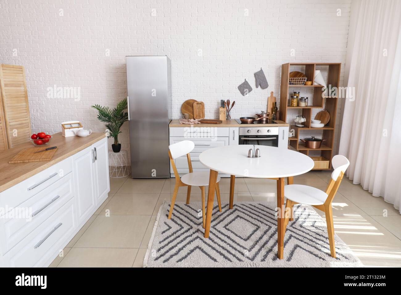 Interior of light kitchen with white counters, fridge and dining table ...