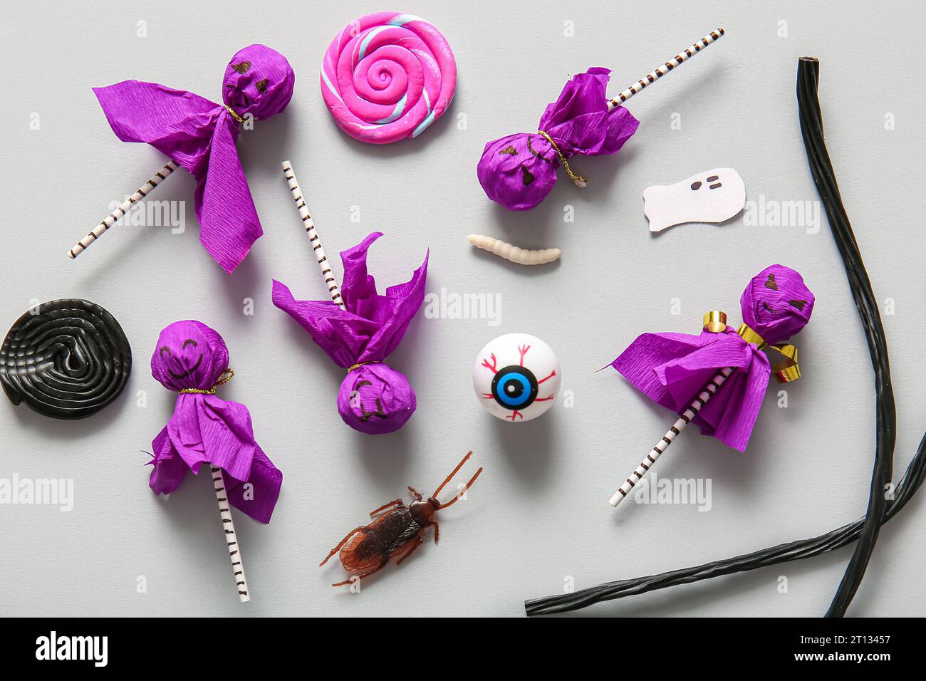 Sweet lollipops with liquorice, jelly eye and cockroach for Halloween party on grey background Stock Photo