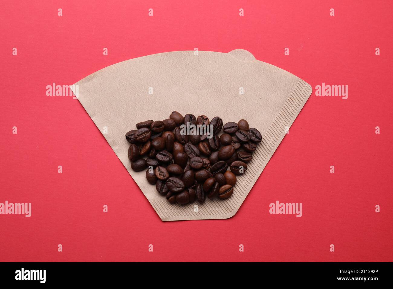 Paper coffee filter and beans on red background, top view Stock Photo