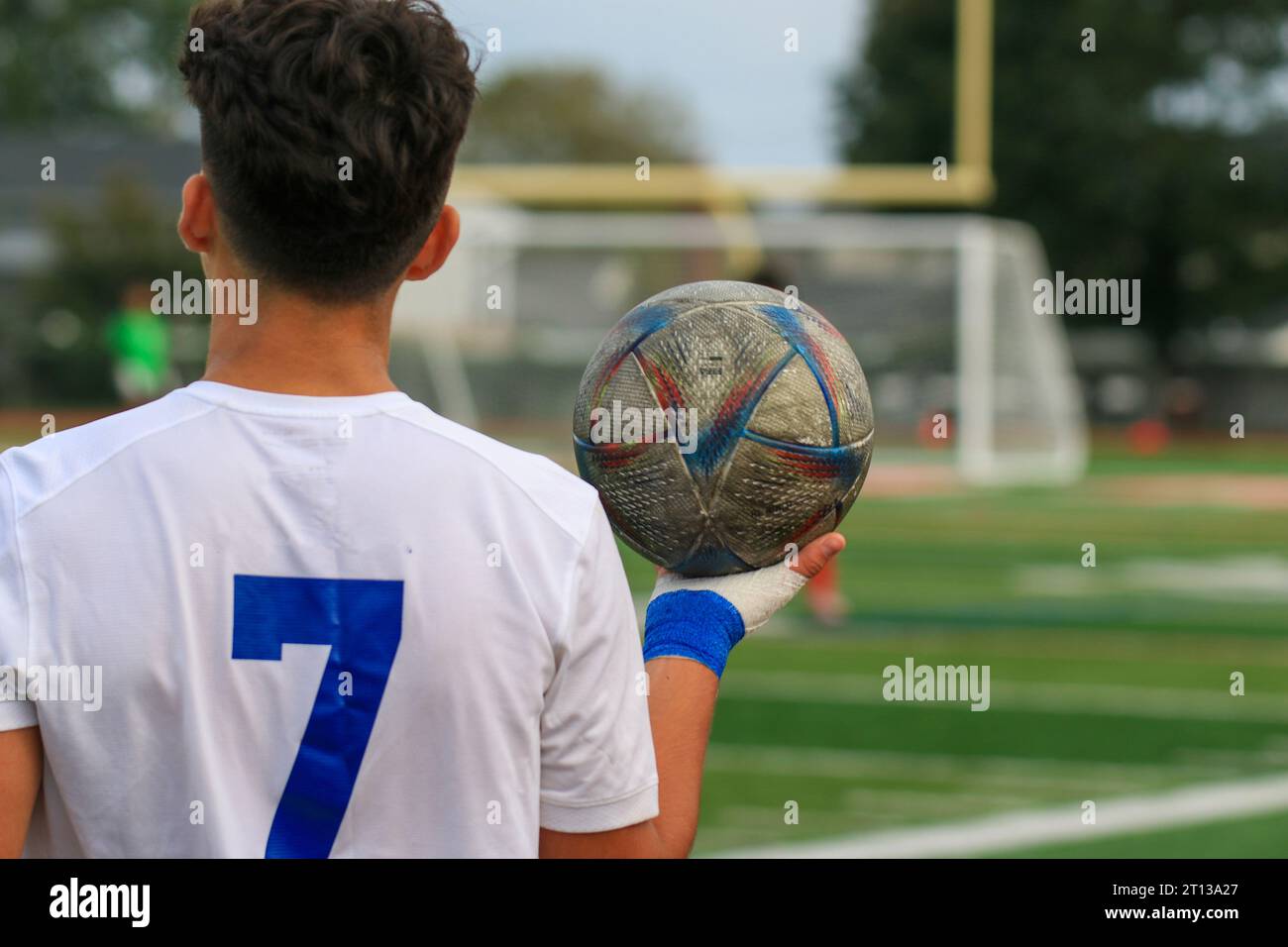 Rear view of a high school soccer player holding the ball in one hand ready for a throw in during a match. Stock Photo