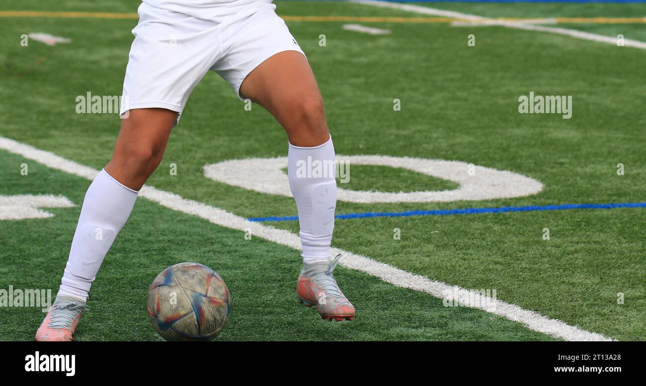 Front view of a high school boy controlling the ball on a green turf field during a soccer game. Stock Photo