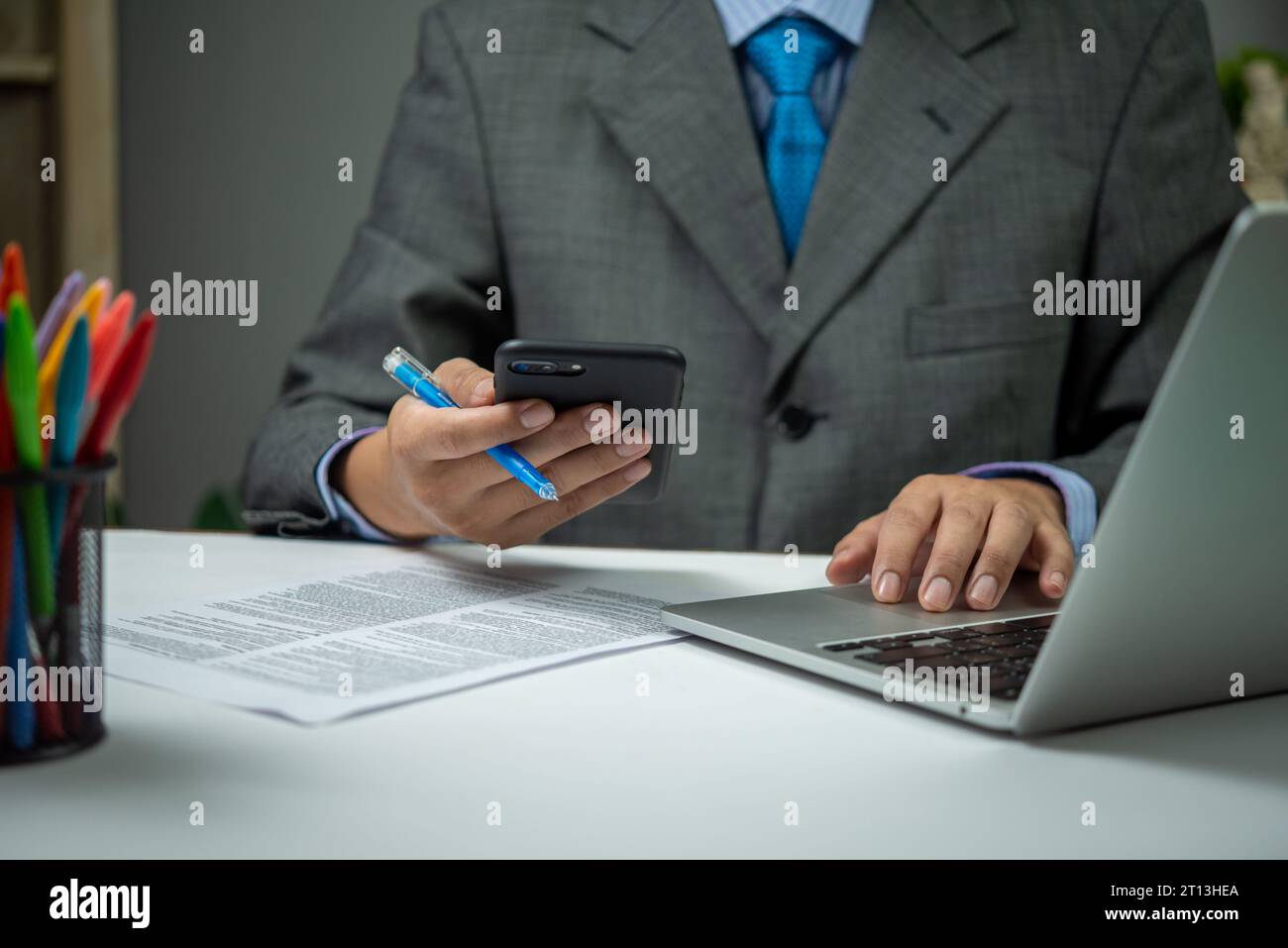 man using smartphone mobile application and document information with laptop on desk. Stock Photo