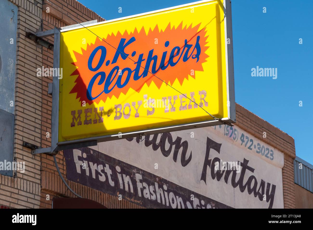 Bright yellow and orange sign for O.K. Clothiers, clothing store for men and boys that opened in 1935 and closed in 2019, Santa Rosa, New Mexico, USA. Stock Photo