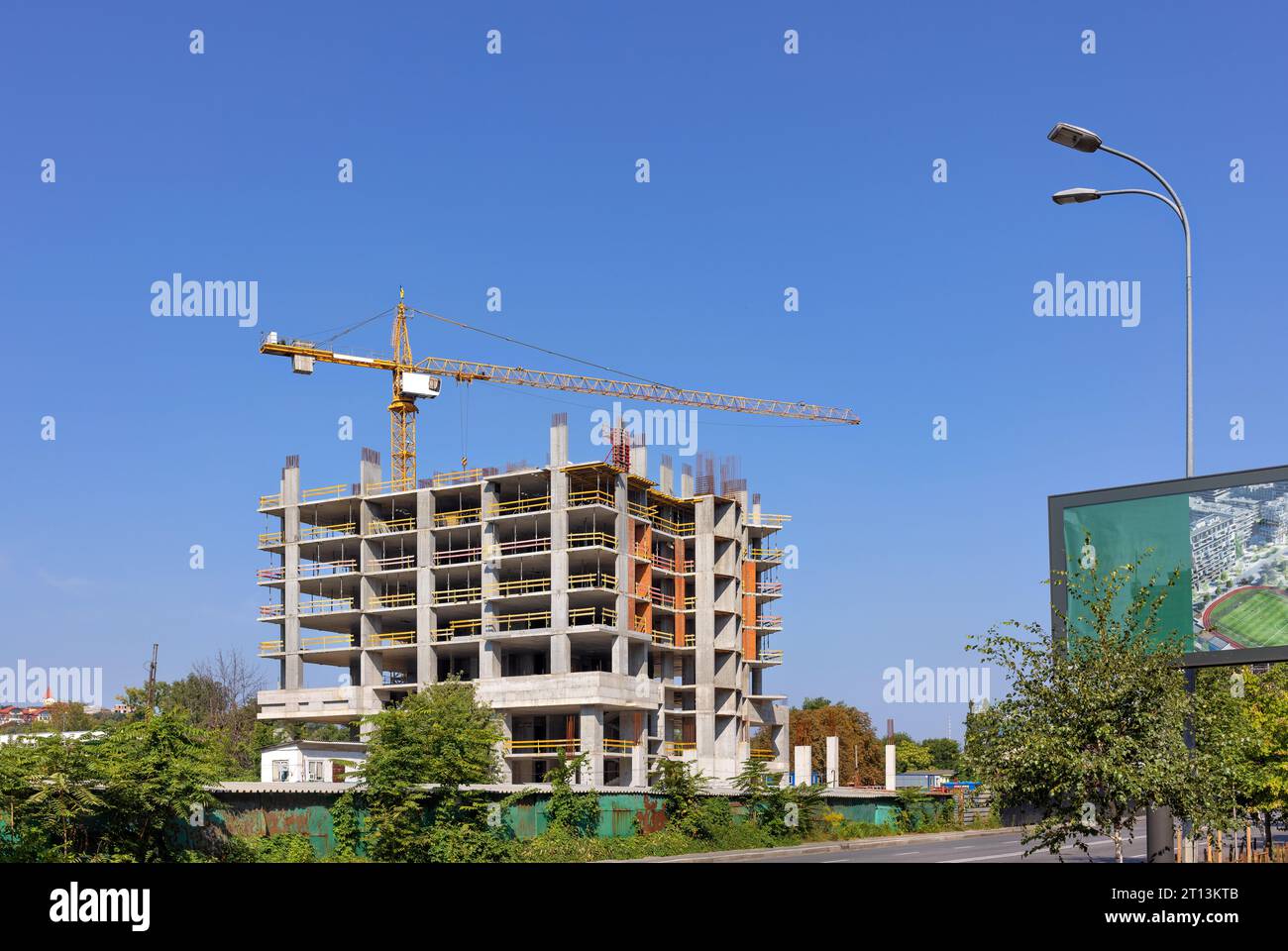 Modern construction of a residential building using the monolithic frame method using a tower crane on a summer day against a blue sky. Copy space. Stock Photo