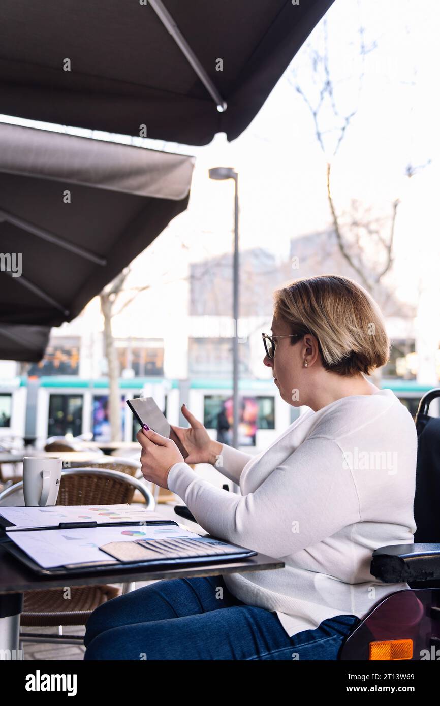 woman using wheelchair working with a tablet Stock Photo