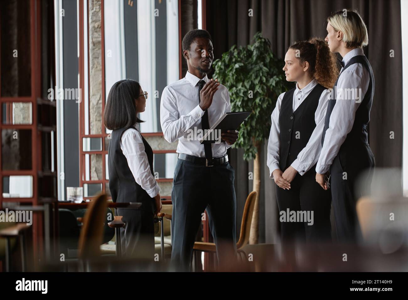 Staff meeting in luxury restaurant with manager talking to three