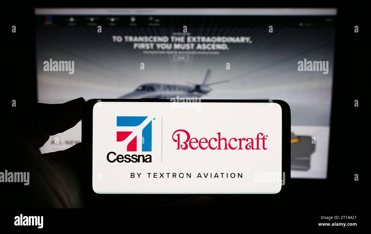 Person holding cellphone with logo of US aviation company Textron Aviation Inc. in front of business webpage. Focus on phone display. Stock Photo