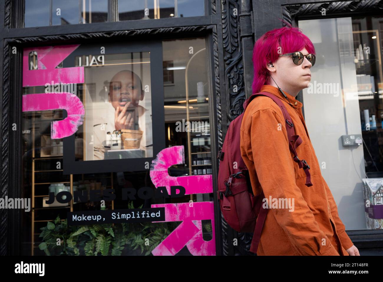 A young person with pink hair passes a window of the retailer Liberty on Great Marlborough Street, on 10th October 2023, in London, England. Stock Photo
